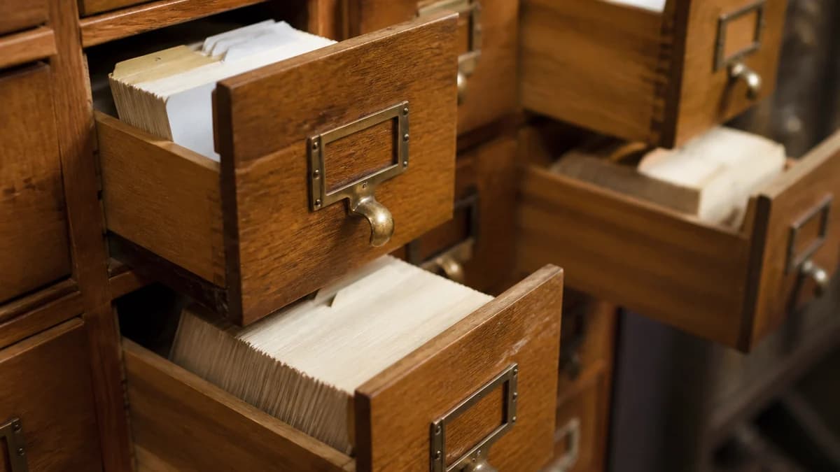 Un catálogo de fichas de biblioteca antiguo con los cajones abiertos y fichas indexadas dentro.